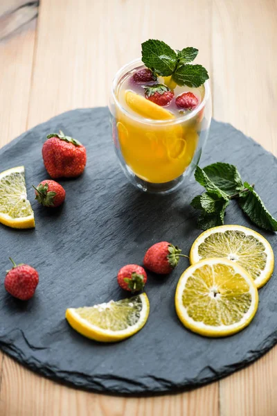 Vista de alto ângulo de bebida fresca deliciosa de verão com hortelã e frutas no tabuleiro de ardósia — Fotografia de Stock