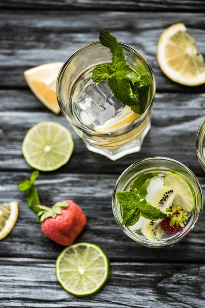 Vue rapprochée des verres avec délicieux cocktail mojito kiwi fraise sur table en bois — Photo de stock