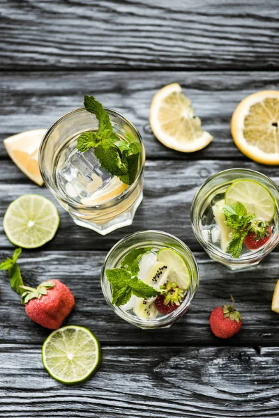 Delicious cold summer cocktail with mint, strawberries and kiwi in glasses on wooden table — Stock Photo