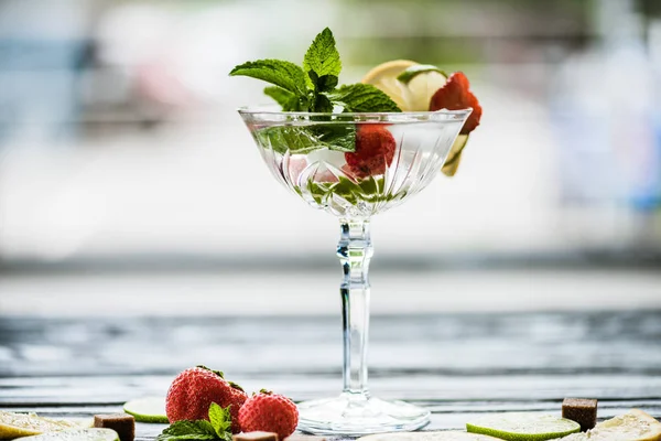 Vista de cerca de delicioso cóctel de verano con menta, lima, limón y fresas en vidrio - foto de stock