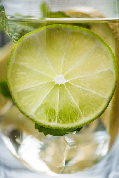 Vista de primer plano de vidrio con mojito fresco frío y rodaja de lima - foto de stock