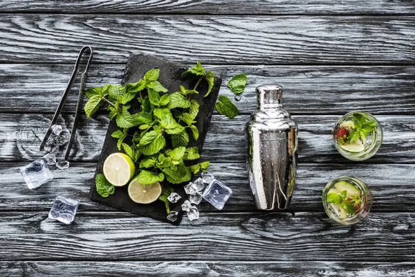 Top view of fresh mint, tongs, shaker and strawberry kiwi mojito in glasses — Stock Photo