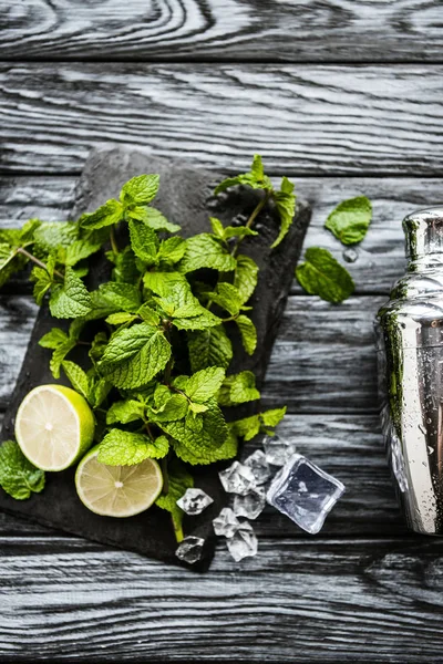 Vue de dessus des ingrédients pour la fabrication de mojito et shaker sur la surface en bois — Photo de stock