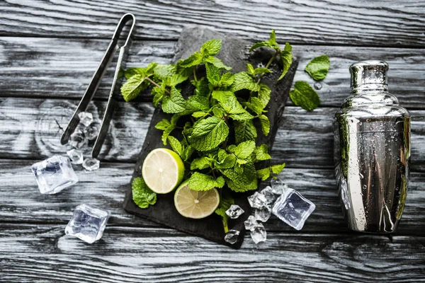 Top view of ingredients for making mojito, tongs and shaker on wooden surface — Stock Photo