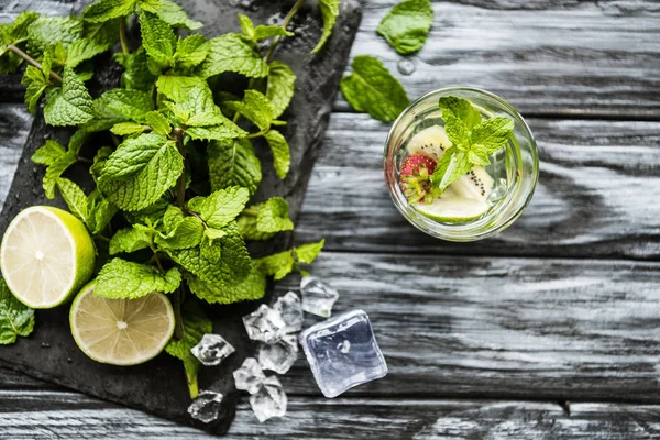 Top view of glass with fresh cold strawberry and kiwi mojito on wooden table — Stock Photo