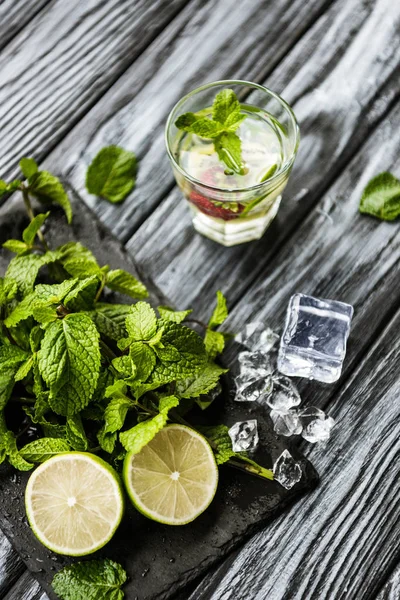 High angle view of glass with fresh strawberry and kiwi mojito on wooden table — Stock Photo