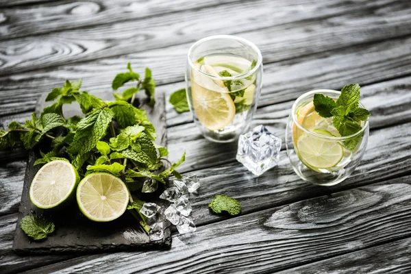 Visão de alto ângulo de óculos com mojito e ingredientes frescos na superfície de madeira — Fotografia de Stock