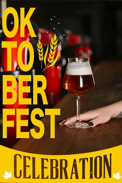 Cropped shot of human hand with glass of fresh beer in bar with 