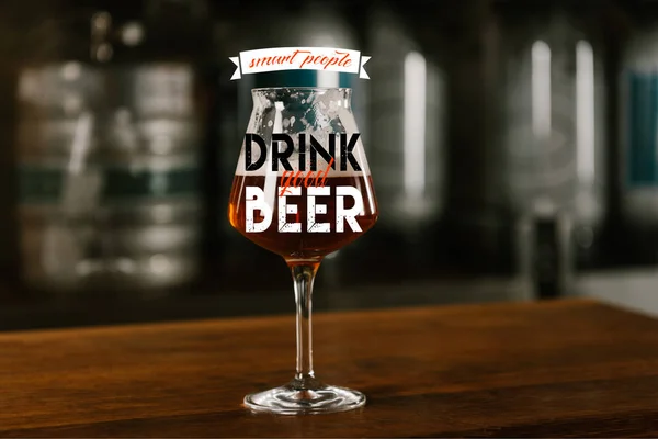 Glass of fresh cold delicious beer on wooden table in pub with 