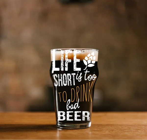 Glass of fresh cold dark beer on wooden table in pub with 