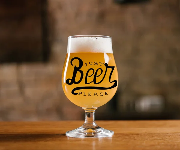 Delicious fresh beer with foam in glass on wooden table in bar with 