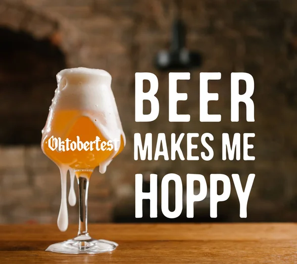 Close-up view of cold beer with foam in glass on wooden table with 