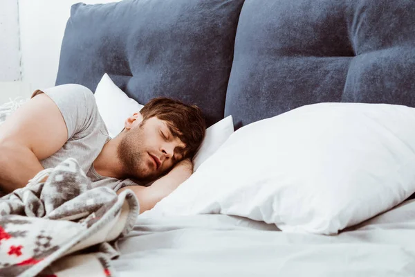 Enfoque selectivo del joven que duerme en la cama en casa - foto de stock