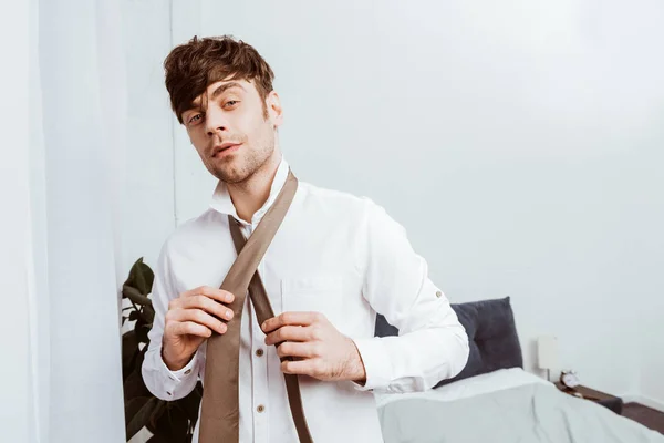 Избирательный фокус бизнесмена в белой рубашке, связывающего шейный галстук дома — стоковое фото