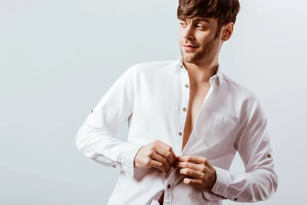 Cheerful businessman buttoning up white shirt isolated on grey — Stock Photo