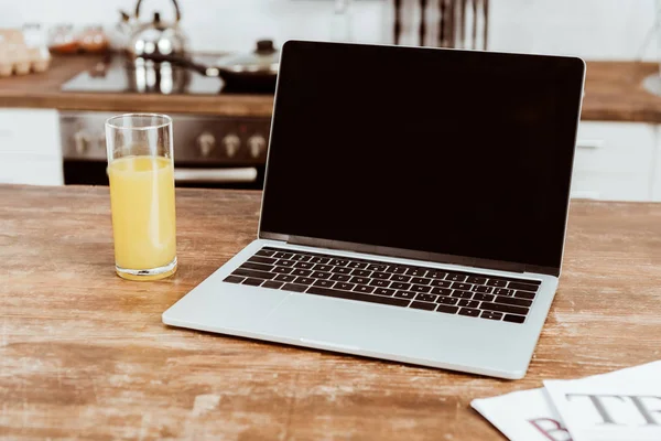 Fuoco selettivo di computer portatile con schermo bianco e succo d'arancia a tavola — Foto stock