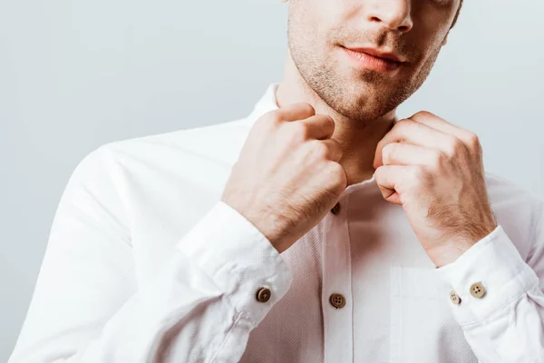 Imagen recortada de hombre de negocios guapo abotonando camisa blanca aislada en gris - foto de stock