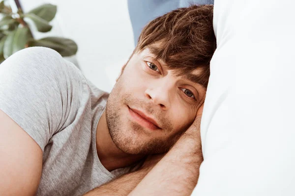 Nahaufnahme Porträt eines Mannes, der in die Kamera schaut und zu Hause im Bett liegt — Stockfoto