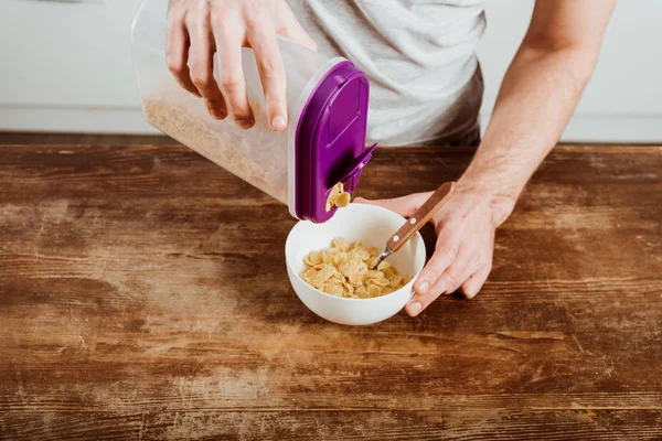 Imagem cortada de fazer café da manhã com flocos de milho à mesa na cozinha em casa — Fotografia de Stock