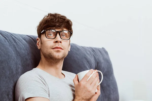 Schöner junger Mann mit Brille und Kaffeetasse zu Hause — Stockfoto