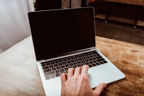 Imagen recortada de freelancer masculino trabajando en el ordenador portátil con pantalla en blanco en la mesa - foto de stock