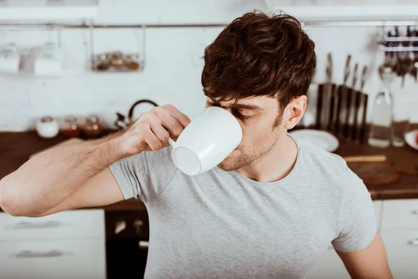 Vista de ángulo alto del hombre bebiendo café en el desayuno en la cocina en casa - foto de stock
