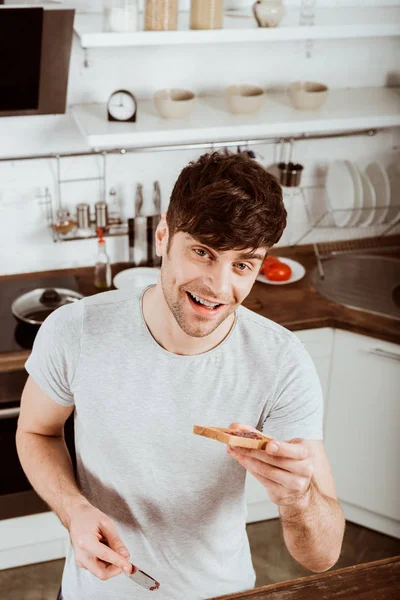 Vue grand angle du jeune homme ayant mangé du pain grillé avec confiture sur le petit déjeuner à la cuisine — Stock Photo