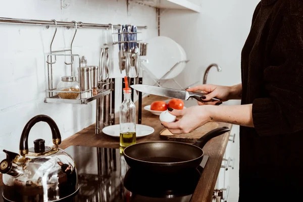 Частичный вид женщины с татуированной рукой, готовящей яйца на завтрак дома — стоковое фото
