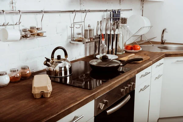 Interior da cozinha moderna com frigideira e bule no fogão — Fotografia de Stock