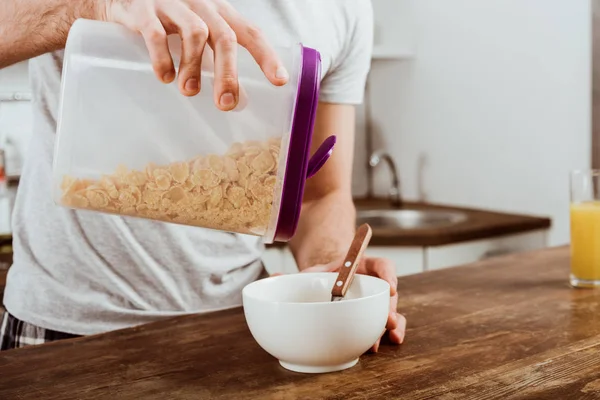 Vue partielle faire le petit déjeuner avec des flocons de maïs dans la cuisine à la maison — Photo de stock