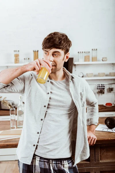 Homem bebendo suco de laranja no café da manhã na cozinha em casa — Fotografia de Stock
