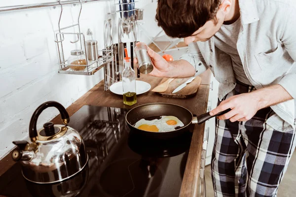 Partial view of young man cooking scrambled eggs on frying pan in kitchen — Stock Photo