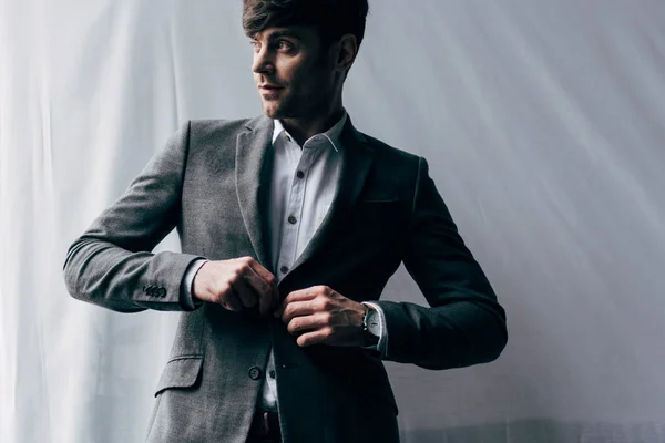 Молодой привлекательный бизнесмен регулируя пиджак костюм — стоковое фото