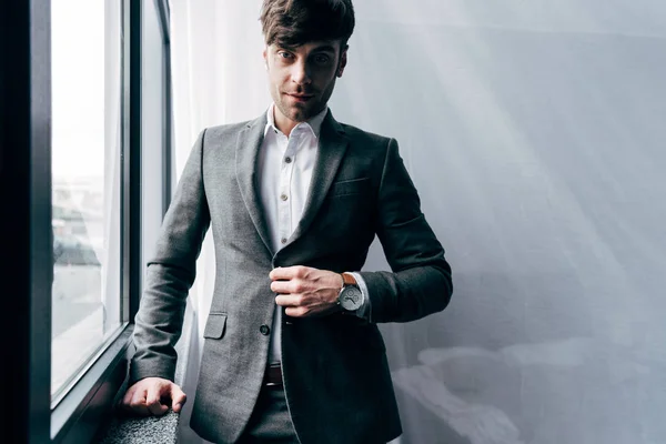 Портрет молодого бізнесмена, що регулює куртку в офісі — стокове фото