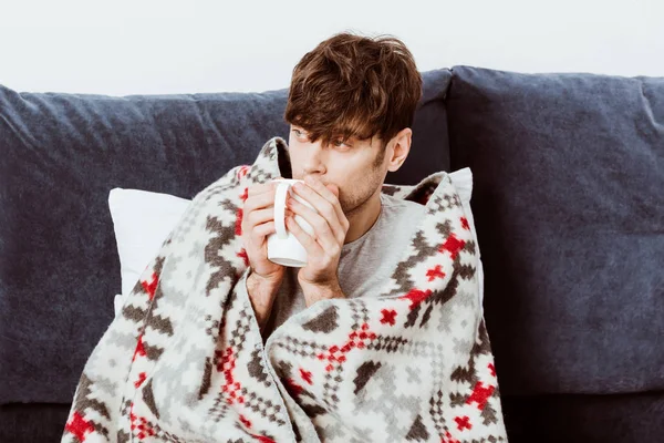 Foco seletivo do homem doente envolto em cobertor beber chá na cama em casa — Fotografia de Stock