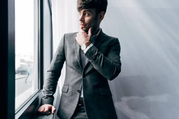 Thoughtful young businessman in jacket looking away in office — Stock Photo