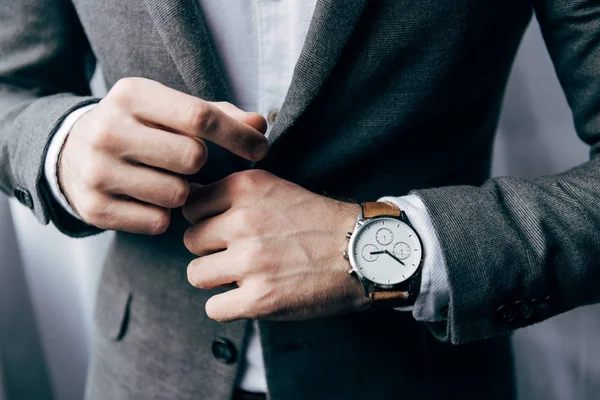 Partial view of businessman with watch buttoning up jacket — Stock Photo