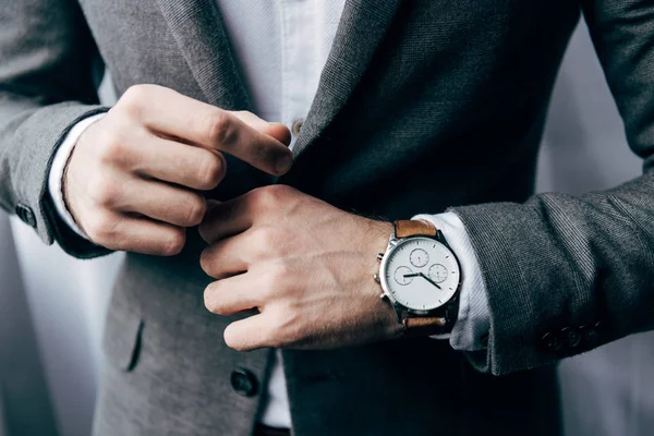 Vista parcial del hombre de negocios con reloj abotonando la chaqueta - foto de stock