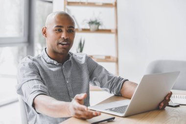 Afrika kökenli Amerikalı işadamı işyerinde laptop ile toplantı sırasında oturan.