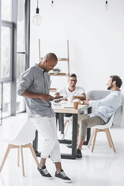 Afroamerikanska Man Använder Surfplatta Medan Kollegor Diskuterar Strategi Arbetsplatsen Office — Stockfoto