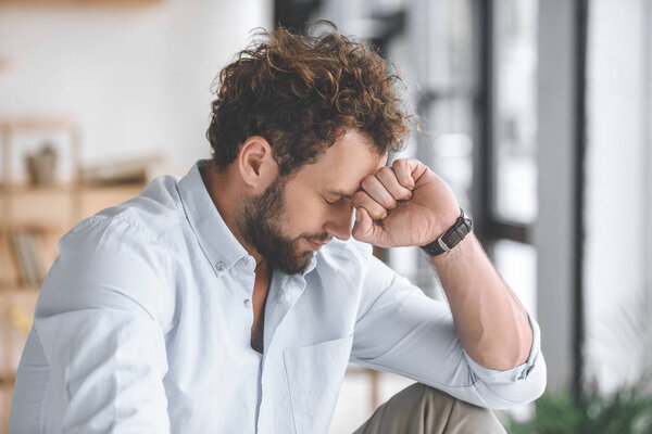 side view of pensive caucasian businessman with eyes closed in office