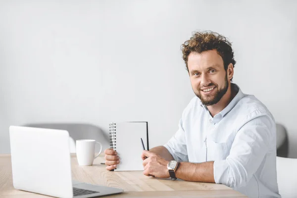 Lächelnder Geschäftsmann Sitzt Mit Laptop Arbeitsplatz Und Zeigt Auf Leeres Stockbild