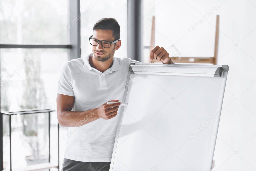 smiling businessman making presentation at white board in office