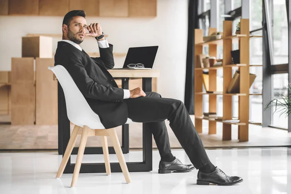 職場のオフィスで座っているハンサムな実業家の側面図 — ストック写真