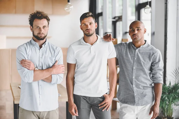 Multiethnic Young Businessmen Looking Camera While Standing Office — Free Stock Photo