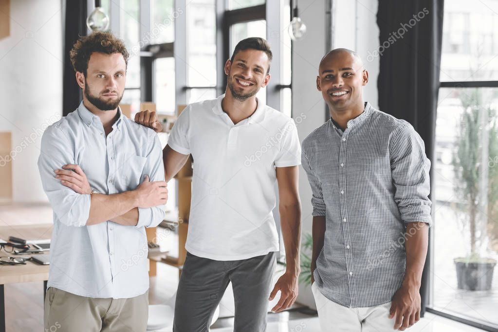 multiethnic young businessmen looking at camera while standing in office