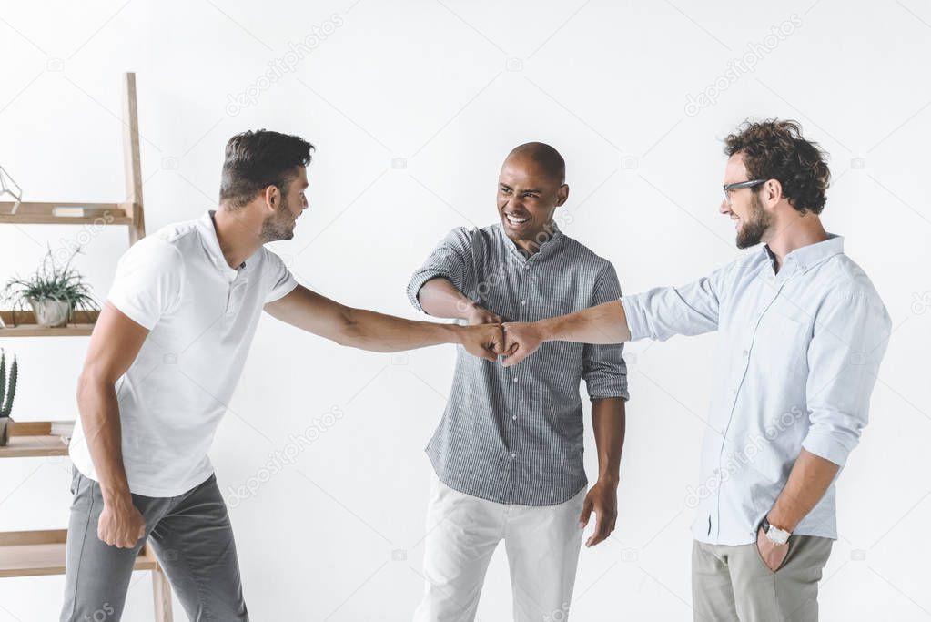 multiethnic group of young businessmen holding hands together