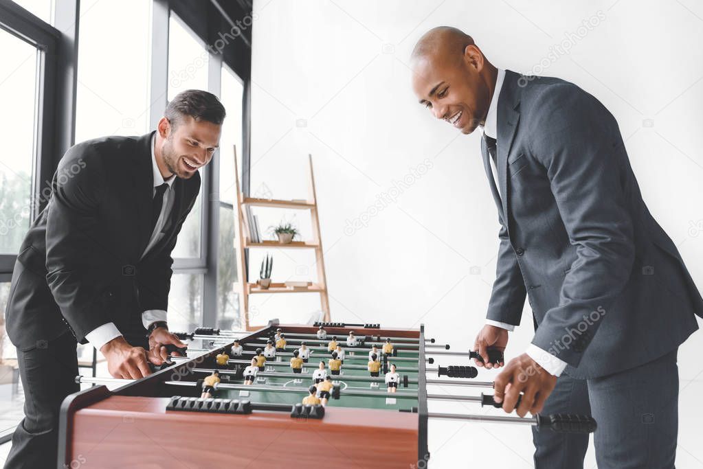 side view of happy businessmen playing table football together