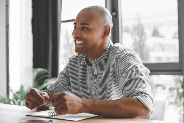 Ritratto di allegro uomo d'affari africano americano seduto sul posto di lavoro in ufficio — Foto stock