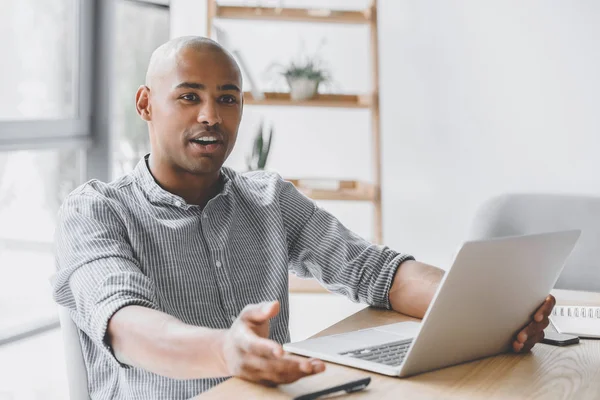 Afrikanisch-amerikanischer Geschäftsmann sitzt mit Laptop am Arbeitsplatz während eines Meetings — Stockfoto